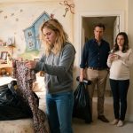 Teenage girl standing in her childhood bedroom as her father holds black trash bags and her stepmother films the confrontation.