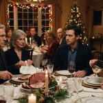 An adult son sitting quietly at a tense family Christmas dinner as his father pauses over the holiday meal and his mother folds her napkin.