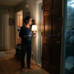 A woman watches a stranger holding a newspaper outside her home after her parents publicly called her a failure and exposed her private information.