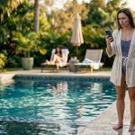 Claire stares anxiously at the mysterious “get on a plane home” message while standing beside her cousin's Florida swimming pool.