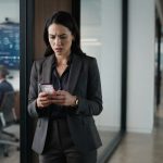 Successful professional woman staring at a troubling phone message after learning she was not invited to the wedding she helped finance.