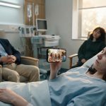A 22-year-old woman wakes after brain surgery in a hospital bed while her grandfather and best friend sleep beside her.