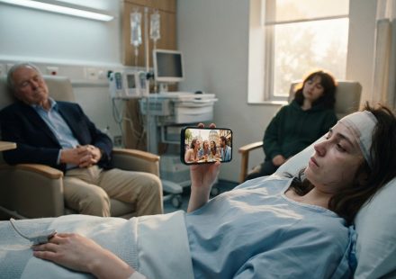 A 22-year-old woman wakes after brain surgery in a hospital bed while her grandfather and best friend sleep beside her.