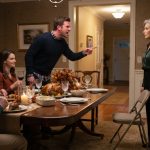 A composed 64-year-old mother facing her angry adult son across a Thanksgiving dining table inside her own home.