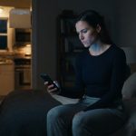 A woman looks at her buzzing phone late at night after her boyfriend texted the group chat to publicly end their relationship.