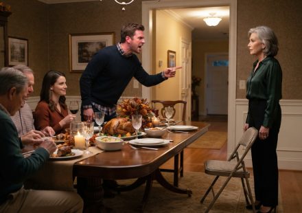 A composed 64-year-old mother facing her angry adult son across a Thanksgiving dining table inside her own home.