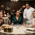 Two sisters at their mother's elegant birthday dinner as a restaurant chef approaches their table beside a brass family recipe box.
