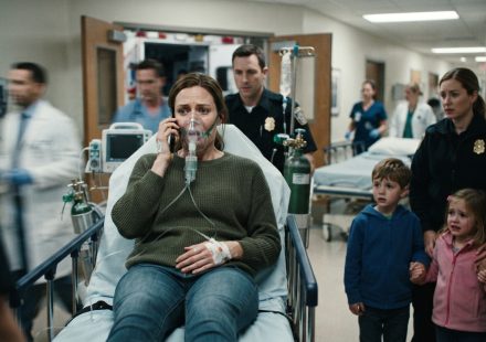 A mother on an ambulance stretcher urgently calls for help while paramedics prepare her for emergency surgery.
