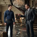 A wealthy father throws dollar bills at his 22-year-old son standing with a suitcase inside an extravagant family mansion.