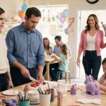 Husband's affair partner at birthday party entering a pottery studio with a silver crown balloon while Violet watches her husband react.