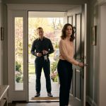 A woman faces her uninvited brother holding a bottle of wine at the front door of her Easter-decorated family home.