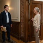 Carter Fisher standing outside his inherited apartment building with property manager Linda Benson as they discuss a mysterious tenant.