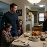 A young daughter denied a plate at Thanksgiving sits beside her protective father while relatives enjoy their holiday dinner.