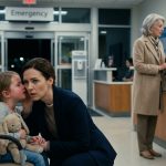 A worried mother holding her feverish five-year-old daughter's hand in a pediatric hospital after Grandma told the doctor not to rush.