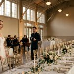 A disappointed bride stands inside an elegant wedding banquet hall surrounded by empty guest chairs after her brother hijacked her wedding date.