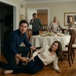 A frightened husband kneels beside his wife during a severe allergic reaction while his elderly mother stands holding a serving spoon at the family dinner table.