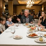 A father sits protectively beside his two young sons at an upscale restaurant, where they have only crackers while their cousins enjoy expensive lobster and steak.