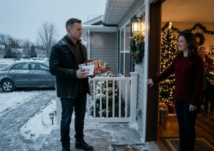 A disappointed man holding wrapped Christmas gifts stands outside his sister's warmly decorated house as she refuses to let him join the family celebration.