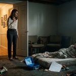 A concerned aunt kneels beside her seriously ill nephew in a neglected room, with a blue lunchbox and suspicious school withdrawal paperwork nearby.