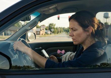 A worried mother sits inside her SUV at a red traffic light, holding herself together while looking at a mysterious message on her phone after learning her young daughter has been injured.