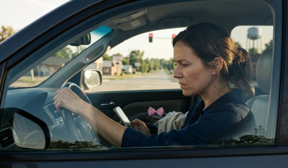 A worried mother sits inside her SUV at a red traffic light, holding herself together while looking at a mysterious message on her phone after learning her young daughter has been injured.