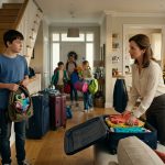A disappointed 13-year-old boy holding his packed backpack watches his parents prepare for a Christmas family vacation while his three siblings get ready to leave without him.